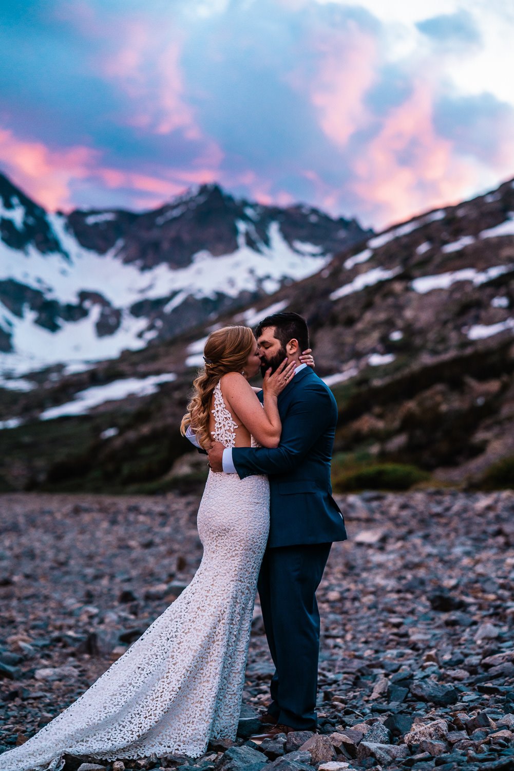 An enchanting elopement photo capturing a passionate kiss between a man and woman with majestic mountains as their backdrop.