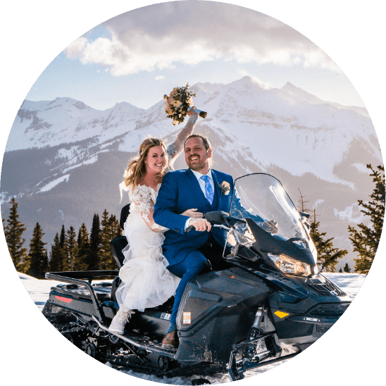 A bride and groom on a snowmobile in the Colorado mountains