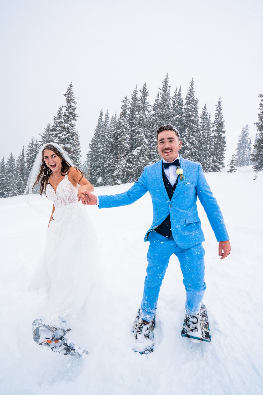 A bride and groom standing on snowshoes in the snow, capturing memorable elopement photos.