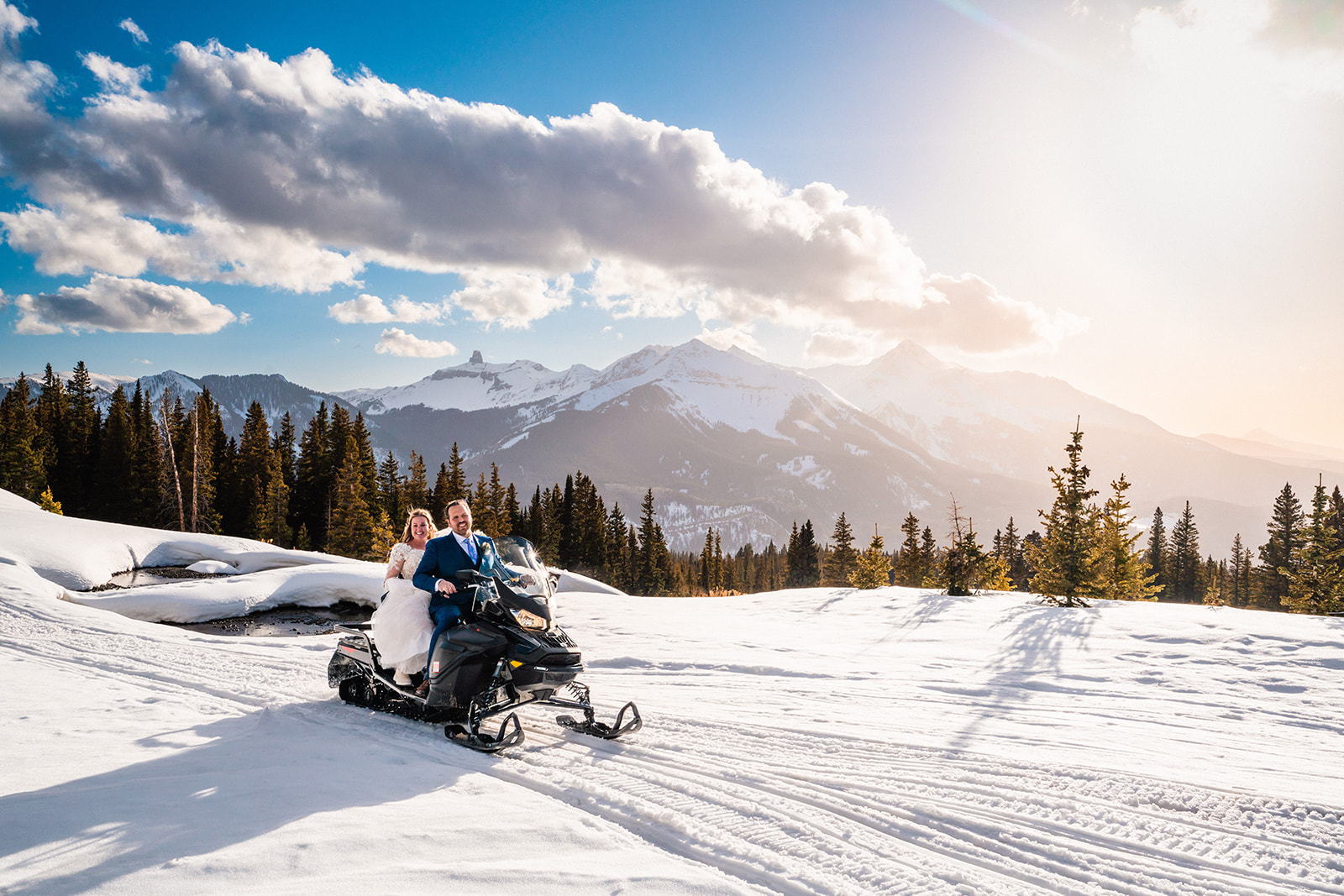 A bride and groom on a snowmobile in the San Juan Mountains after their Telluride elopement.