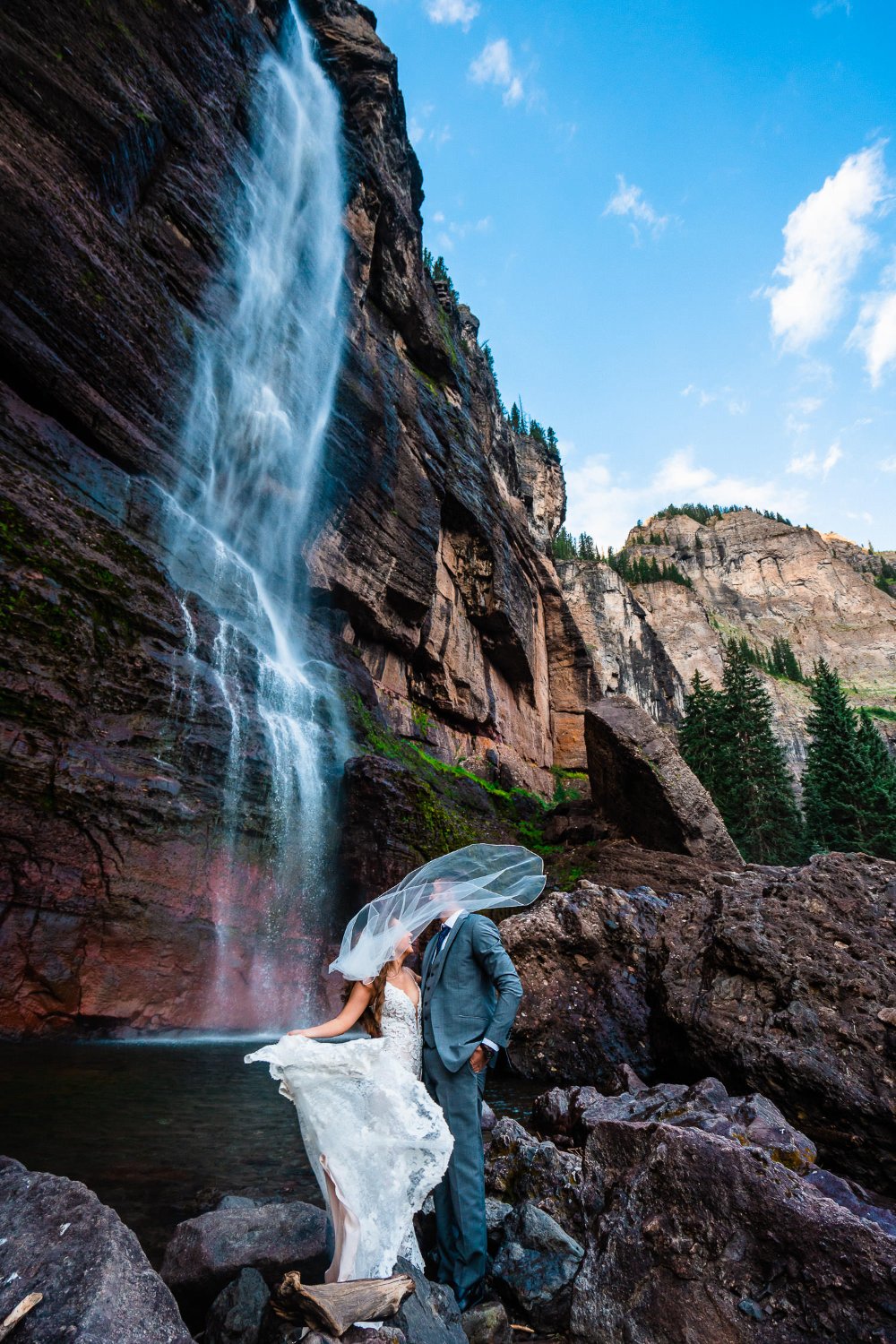 A bride and groom capturing unforgettable elopement photos in front of a stunning waterfall.