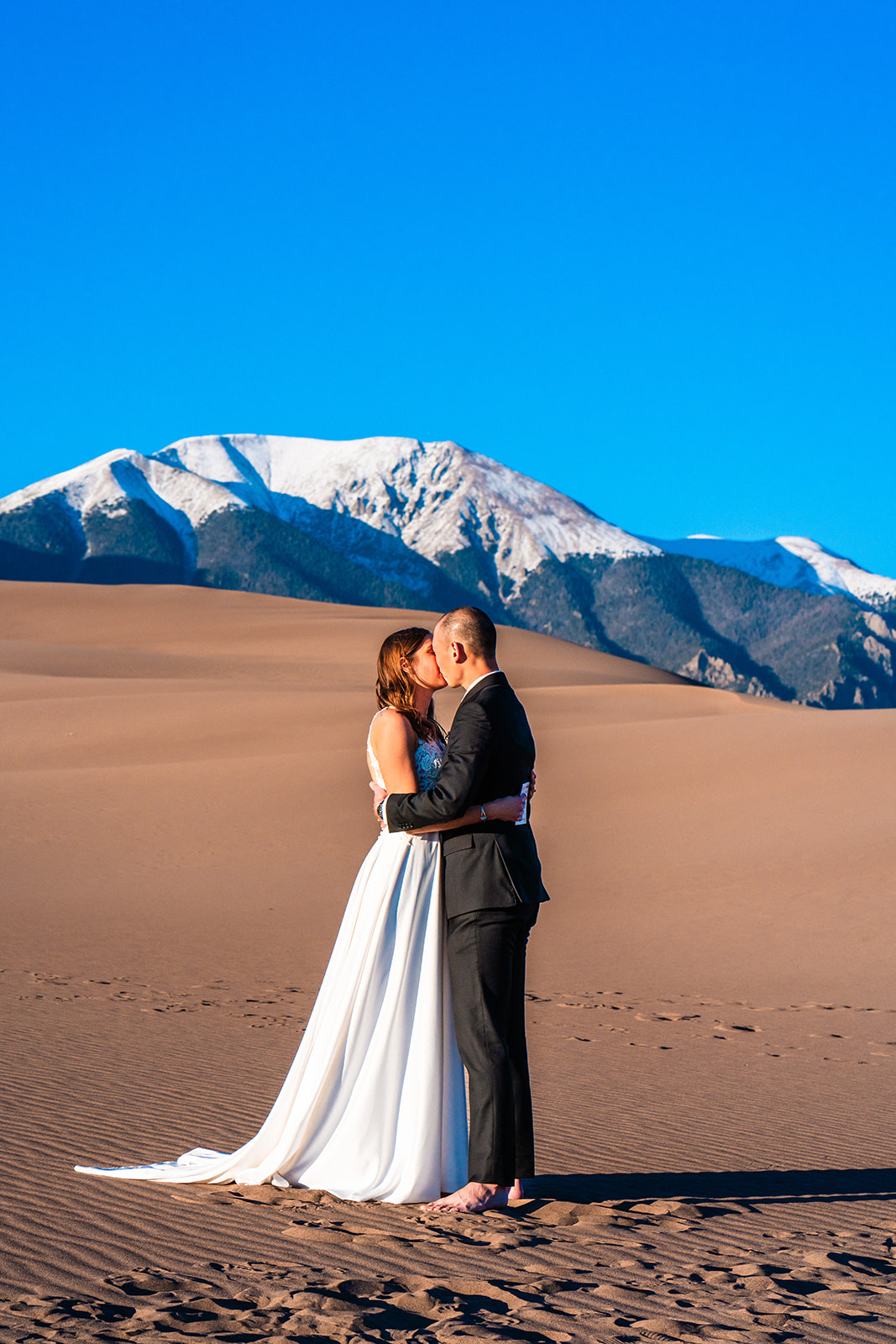 A bride and groom kiss during their Colorado elopement in the Great Sand Dunes, one of the best places to elope in Colorado.
