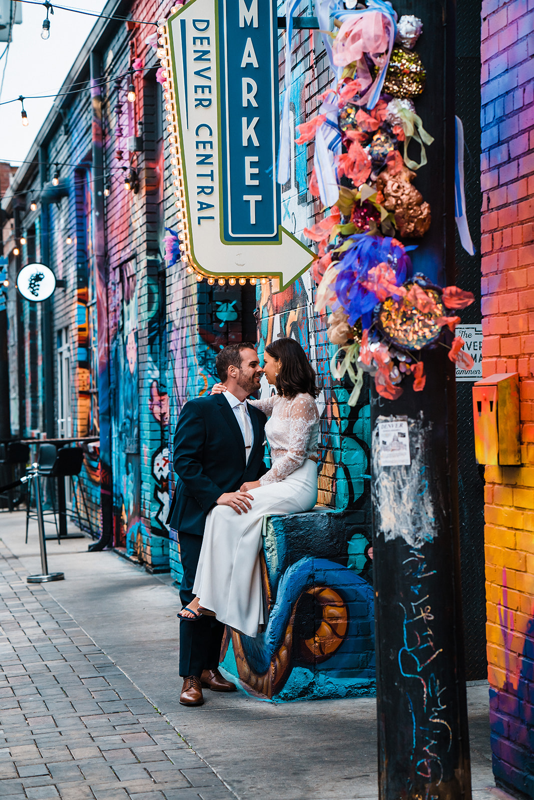 A bride and groom snuggle in front of a colorful mural in one of the best places to elope in Colorado during their Denver elopement.