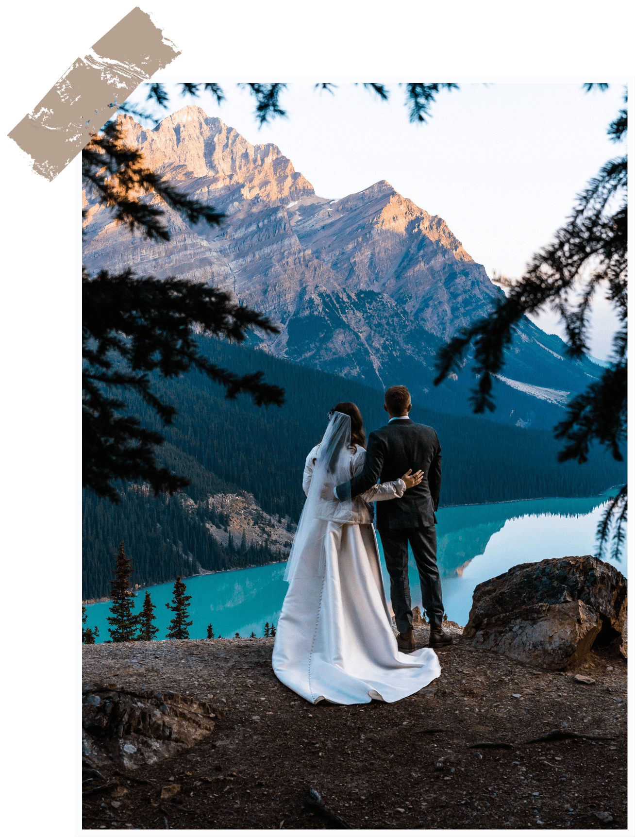 a bride and groom standing on a cliff overlooking Colorado mountains and lake